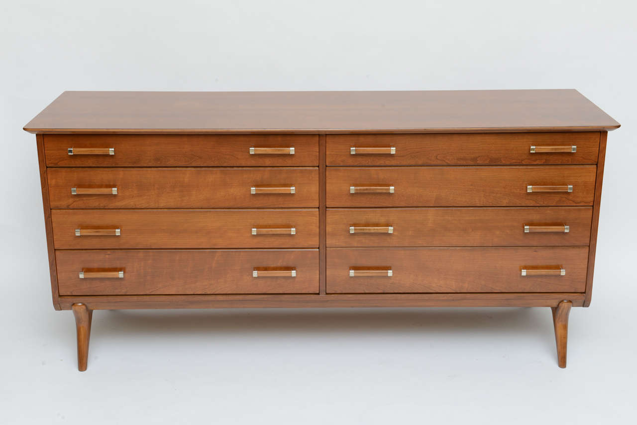 Beautifully figured cherrywood throughout highlights this eight drawer dresser designed by Renzo Rutili for Johnson Furniture and deftly restored.
1950s modern lines, sculptural legs, sophisticated wood pulls with polished brass mounts, exceptional